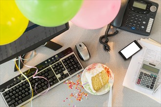 Studio shot of office workspace with cake and balloons.