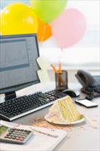 Studio shot of office workspace with cake and balloons.