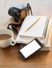 Studio shot of notepads, smartphone, camera and coffee.