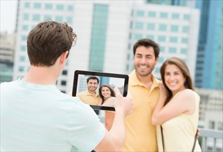 Man using tablet pc to take picture of friends.