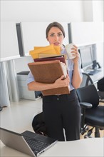 Business woman holding stack of documents in office.