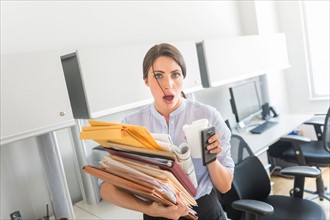 Business woman holding stack of documents in office.