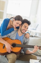 Man playing guitar while woman embracing him.