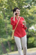 Mature woman talking on cell phone in park.
