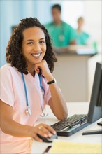 Portrait of smiling female doctor working at desks in hospital.
