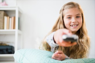 Girl (8-9) holding remote control