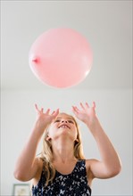 Girl (8-9) playing with pink balloon