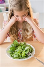 View of unhappy girl (8-9) with salad
