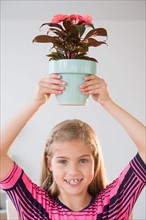Portrait of girl (8-9) holding flower pot