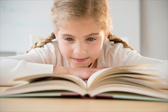 Portrait of girl (8-9) reading book