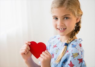 Portrait of blond girl (8-9) in hospital with paper heart