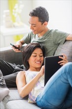 Young people using mobile phone and digital tablet on sofa
