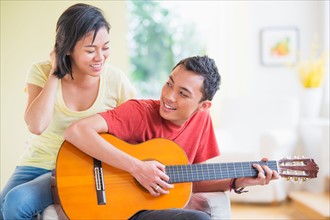Young man playing guitar, woman listening