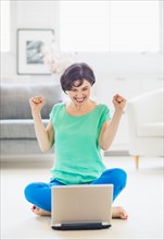 Young woman cheering in front of laptop