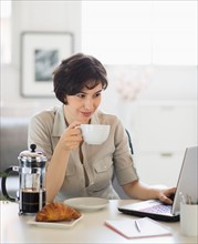Portrait of woman having coffee and using laptop