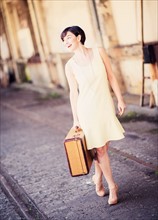 Woman in dress holding suitcase at train station