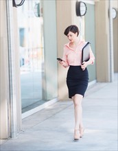 Portrait of business woman walking and text messaging