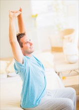 Man sitting on bed and stretching