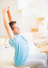 Man sitting on bed and stretching