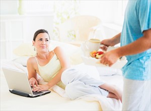 Man serving breakfast to woman in bed