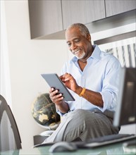 Portrait of senior man using digital tablet in office
