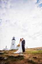 Portrait of married couple kissing, lighthouse in background