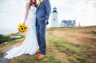 Low section of married couple, lighthouse in background
