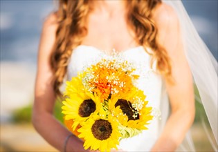 Mid section of bride holding sunflower bouquet