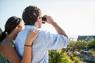 Rear view of couple, man looking through binoculars