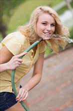 Portrait of young woman holding garden hose
