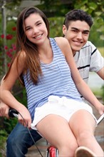 Portrait of sister and brother (14-15) having fun on bicycle