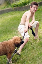 Boy (12-13) and his dog playing with rope