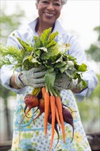 Portrait of senior woman holding carrots and beetroot