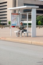 Senior man sitting at bus stop with fishing rod