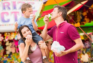 Happy family with son (4-5) in amusement park eating cotton candy