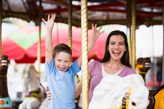 Mother and son (4-5) on carousel in amusement park