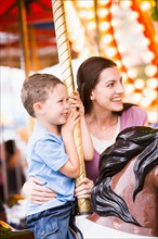Mother and son (4-5) on carousel in amusement park