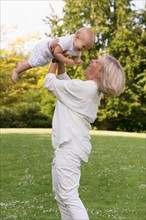 Grandmother holding her granddaughter (12-17 months) in air