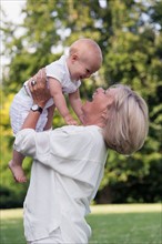 Grandmother holding her granddaughter (12-17 months) in air