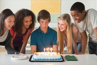 Children (12-13,14-15,16-17) blowing candles on birthday cake