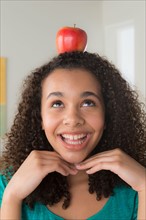 Girl (-12-13) carrying apple on her head