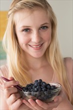 Girl (14-15) holding bowl of black berries