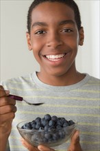 Boy (14-15) holding bowl of black berries