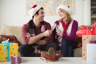 Portrait of young couple wearing santa hats drinking champagne