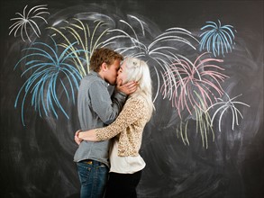 Studio portrait of young couple embracing in front of blackboard