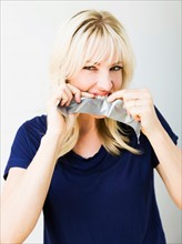Studio portrait of blonde woman ripping tape