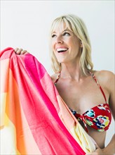 Studio portrait of blonde woman wearing bikini and holding towel