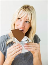 Studio portrait of blonde woman eating chocolate