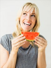 Studio portrait of blonde woman eating watermelon