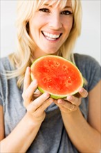 Studio portrait of blonde woman eating watermelon